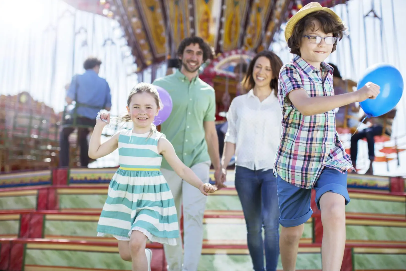 Joyful family walking at carnival carousel with balloons